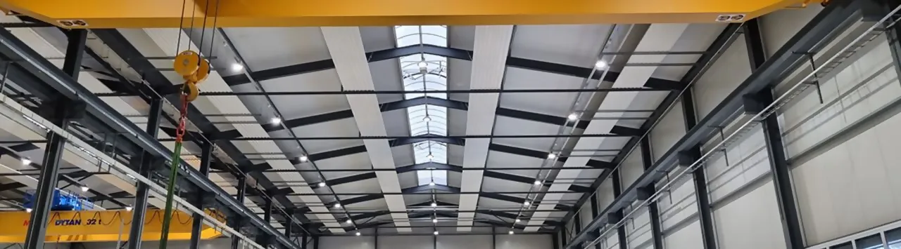 Decke einer Industriehalle, an der Leuchten und Sensoren zu sehen sind