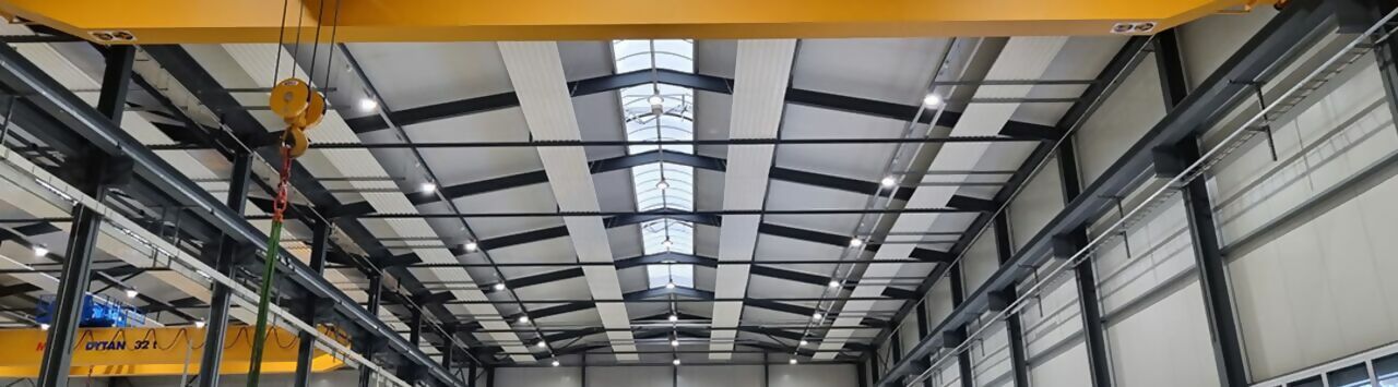 Plafond d'un hall industriel, sur lequel on peut voir des lampes et des capteurs