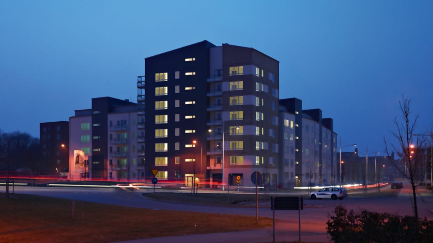 neunstöckiger beleuchtetet wohnungsbaukomplex bei Dämmerung