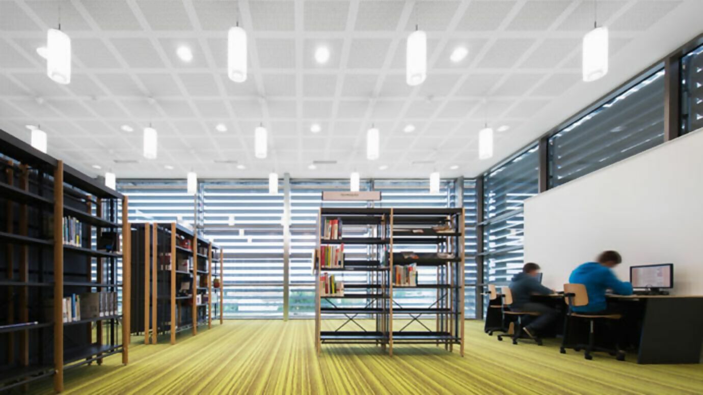 Dos personas estudiando en una biblioteca vacía.